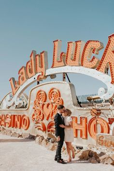 a newly married couple standing in front of the neon sign for las vegas hotel and casino