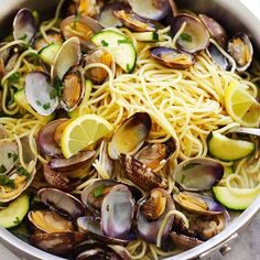 pasta with clams, zucchini and lemon slices in a pan on the table