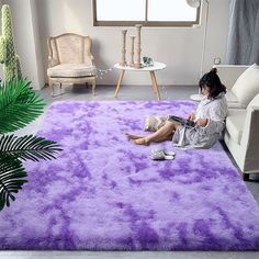 a woman sitting on the floor in front of a purple area rug that looks like she is reading