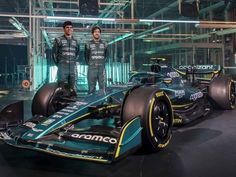 two men standing next to a racing car in a building with lights on the side