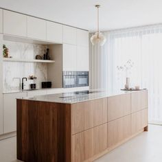 a kitchen with white cabinets and marble counter tops, along with an island in the middle