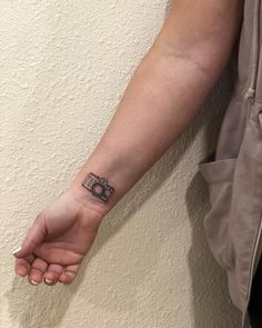 a woman's arm with a camera tattoo on the left side of her wrist