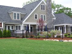 a house with a black fence in front of it and green grass on the ground