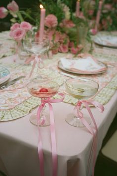 the table is set with two wine glasses and pink napkins on top of it