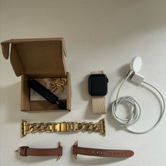 an apple watch and other accessories are laid out on a white table top, with the box open