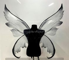 a black and white photo of a dress form with wings on it's head