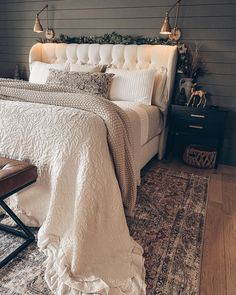 a white bed sitting on top of a wooden floor next to a chair and rug