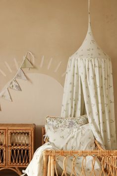 a wicker bed with white sheets and pillows in a room decorated with bunting flags