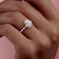 a woman's hand with a diamond ring on her finger and the other hand holding an engagement ring