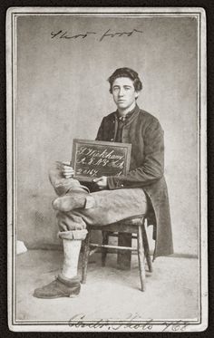 an old black and white photo of a man sitting in a chair holding a chalkboard