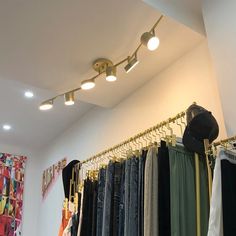 a room filled with lots of clothes hanging on the wall and lights above them that are dimming