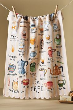 a tea towel hanging on a clothes line with cups and saucers drawn on it