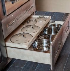 an open drawer with pots and pans on it in the middle of a kitchen