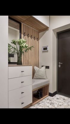 a room with a bench, mirror and vase on the wall next to a door