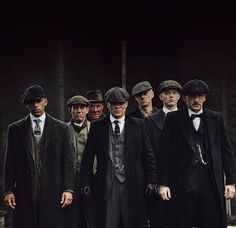 a group of men standing next to each other in suits and ties, all wearing hats