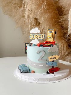 a birthday cake with cars on it and the number two written on top is sitting on a white table