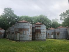 an old grain silos sitting in the middle of a field with trees behind them