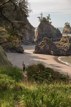 a person standing on the edge of a cliff looking out at the water and rocks