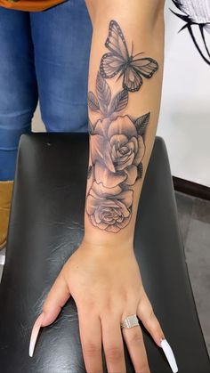 a woman's hand with a butterfly and rose tattoo on her left arm, sitting on a black chair