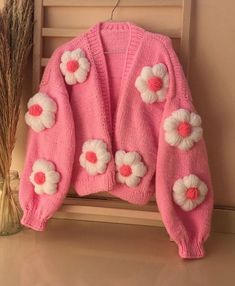 a pink sweater with white flowers on it