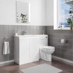 a white toilet sitting next to a sink in a bathroom under a window with potted plants on the ledge