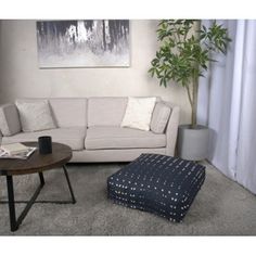 a living room with a couch, ottoman and coffee table in front of a painting