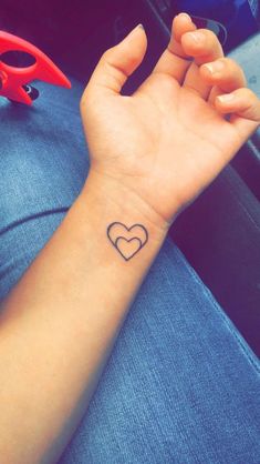 a small heart tattoo on the wrist