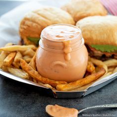 a plate with french fries and a jar of peanut butter on it next to some burgers