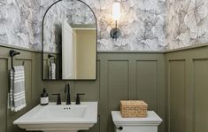 a white toilet sitting next to a sink in a bathroom under a wall mounted mirror