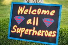 a sign that says welcome all superheros on it in front of a tree and grass area