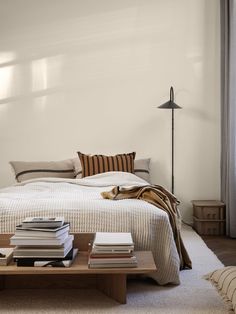 a bed sitting next to a table with books on top of it in a bedroom