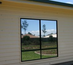 a white building with two large windows on the side and grass in front of it