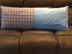 a brown couch with a plaid pillow on it's back and a blue cushion