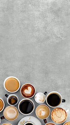 several cups of coffee are arranged in the shape of a heart on a gray background