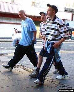 four men walking down the street with one holding a cell phone