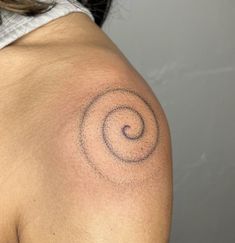 a woman's shoulder with a tattoo on the back of her arm and an abstract spiral design