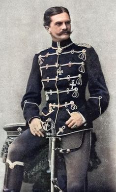 an old photo of a man in uniform sitting on a chair and holding a cane