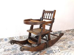 an old wooden rocking chair sitting on top of a tiled floor