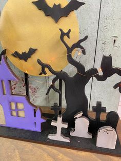 a halloween scene with bats, tombstones and a full moon on a wooden surface