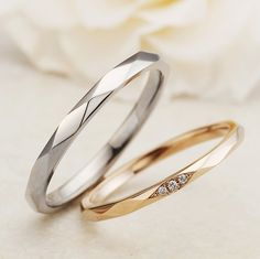 two gold and silver wedding rings with diamond stones on the side, sitting next to each other