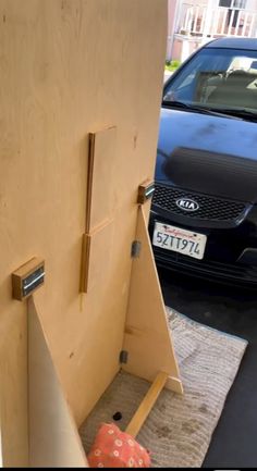 a car is parked in front of a wooden door with an opening to the outside