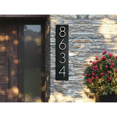 a house number sign on the side of a building next to a potted plant