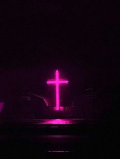 a cross lit up in the dark at night