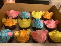 a box filled with lots of colorful cupcakes on top of a countertop