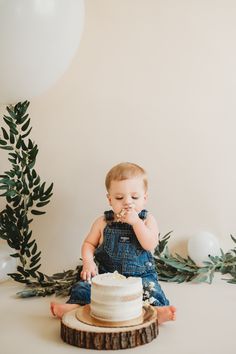 a small child sitting on top of a table with a cake in front of him