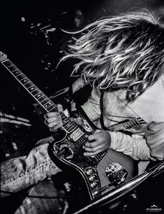 a young man with long hair playing an electric guitar in a black and white photo