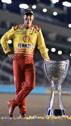 a man standing next to a trophy on top of a race track