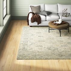 a white couch sitting on top of a hard wood floor next to a wooden table