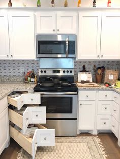 a kitchen with white cabinets and stainless steel stove top oven, pull out drawers in the middle