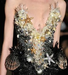 a close up of a person wearing a dress made out of seashells and pearls